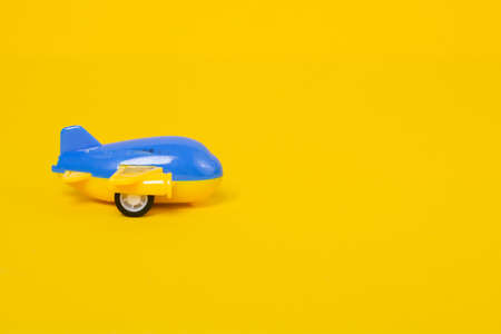Baby toy airplane on yellow background with copy space. Blue airplane on colored background. Children's toys concept. Travel and vacation conceptの写真素材