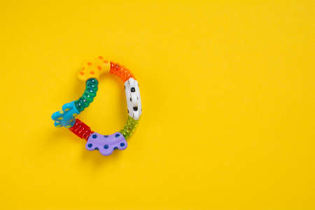 Top view a colorful baby rattle on yellow background with copy space. Flat lay newborn rattle toy on colored background. Baby toys conceptの写真素材