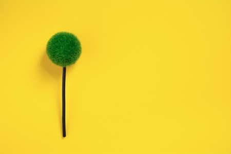 Decorative green flower on the yellow background with copy space. Artificial flower on colored background flat layの写真素材