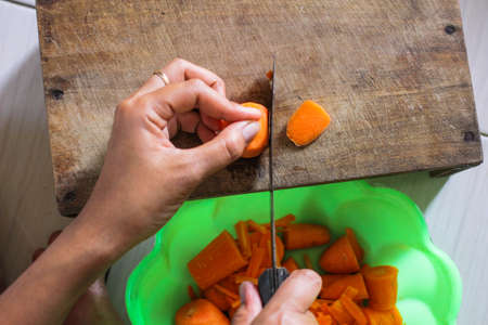 Cutting fresh carrot pieces on wooden boardの写真素材