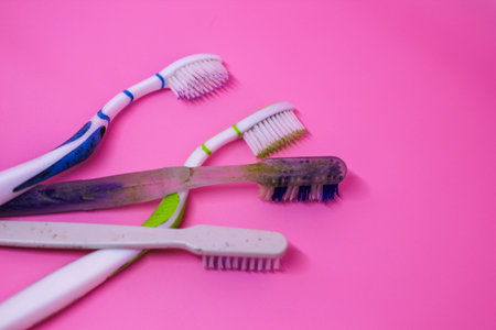 Old broken toothbrush on pink backgroundの写真素材