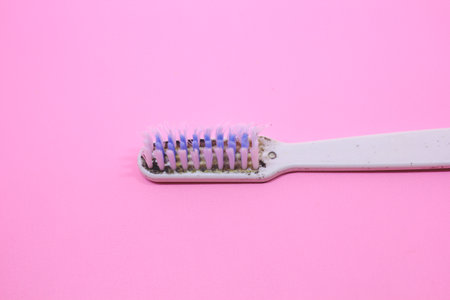 Old broken toothbrush on pink backgroundの写真素材