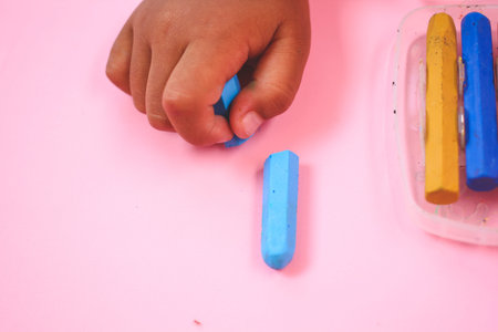 Multicolored broken crayon on pink background
