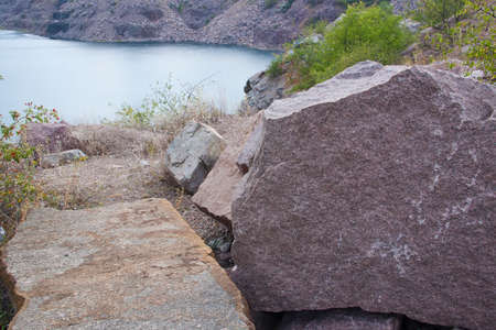 Old granite quarry with water. Large raw pieces of stone.の写真素材