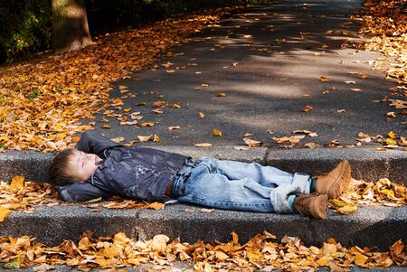 child resting on steps in Autumn.の写真素材