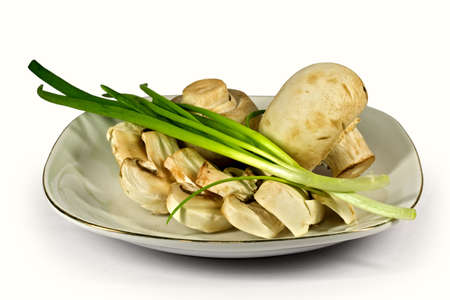 Champignons with a green onions on the white porcelain plate, isolated on a white background.の写真素材