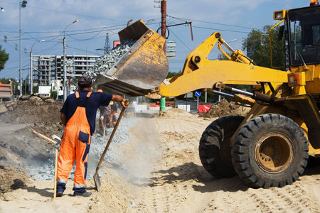 Worker and road loader on construction of road.