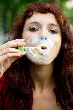 Young woman blowing bubbles on nature.