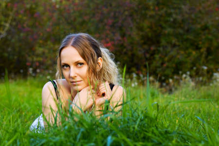 Happy young woman lying on the green grass.の写真素材