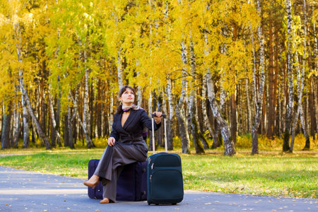 Young businesswoman sitting on a luggage ready for travel.の写真素材