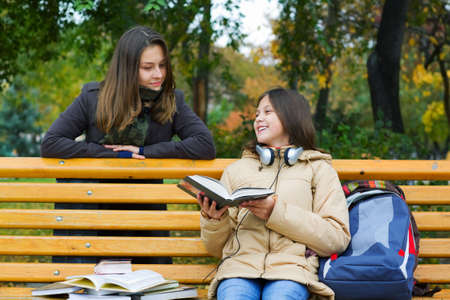 Two young teenage friends reading in the park.の写真素材