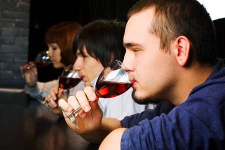 Young people drinking red wine on a bar counter.の写真素材