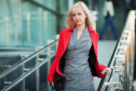 Young businesswoman on the stairs against office windows.の写真素材