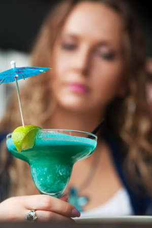 Sad young woman with a cocktail.の写真素材