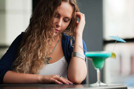 Sad young woman with a cocktail.の写真素材