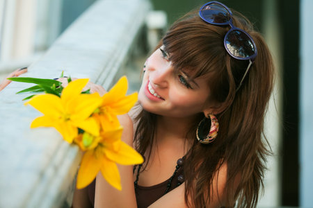 Happy young woman with a yellow lily.の写真素材