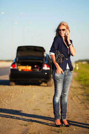 Young woman with a broken car calling for helpの写真素材
