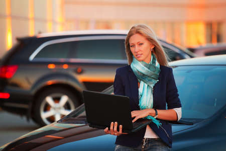 Young businesswoman with laptop on the parkingの写真素材