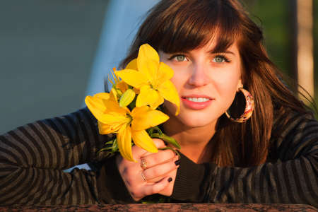 Happy young woman with a yellow liliesの写真素材