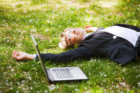 Happy businesswoman lying on a grassの写真素材