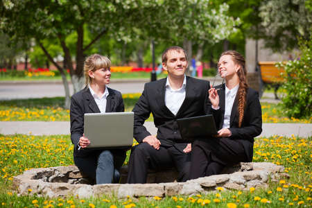 Business people with laptop in a city parkの写真素材
