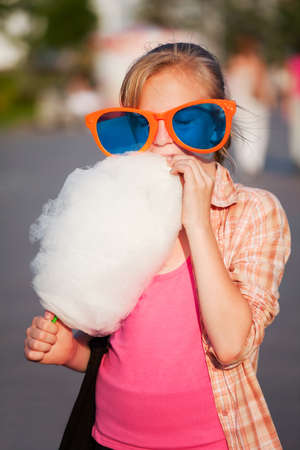 Girl eating cotton candyの写真素材