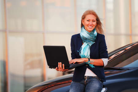 Young businesswoman using laptop against office windowsの写真素材
