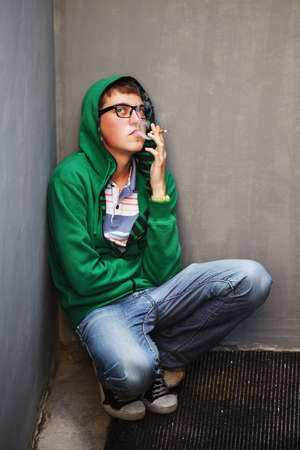 Young man in depression smoking a cigaretteの写真素材