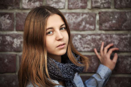 Teenage girl against a brick wallの写真素材