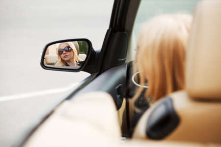 Young woman looking in the car mirrorの写真素材