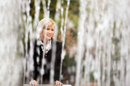 Happy young woman against a city fountainの写真素材