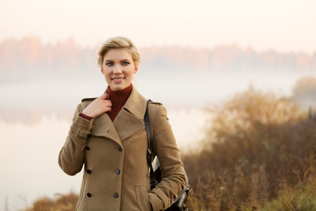 Happy young woman against a morning foggy landscapeの写真素材