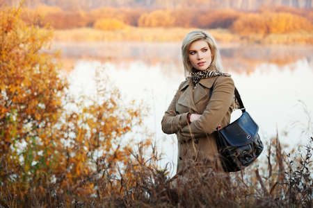 Blond woman against an autumn nature landscapeの写真素材