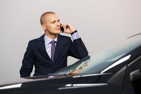 Young businessman calling on the phone at the car