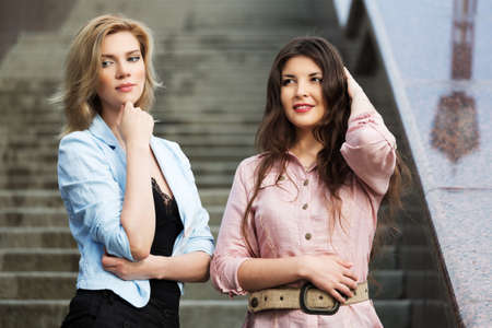 Two happy young women standing on the stepsの写真素材