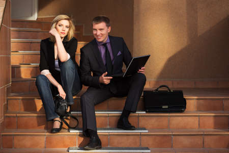 Young business couple with laptop on the stepsの写真素材