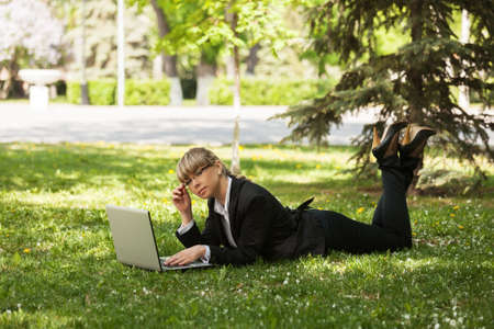 Happy business woman using laptop in a city parkの写真素材
