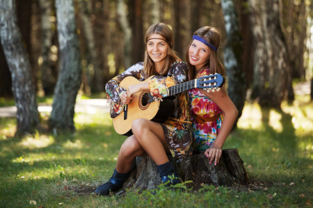 Two hippie girls with guitar in a summer forestの写真素材