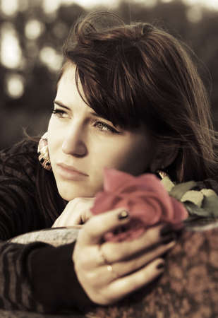 Sad young woman with a red rose の写真素材