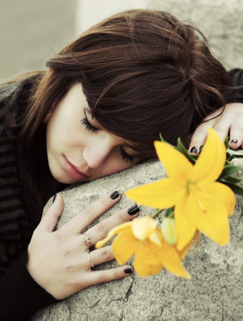 Sad young woman lying on the tombstone 