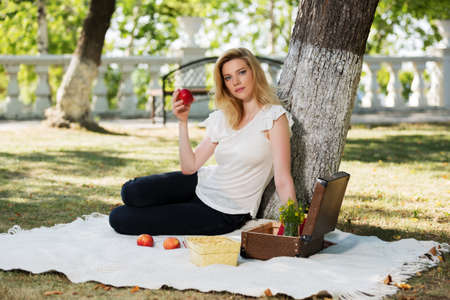Young fashion woman with apple in a city parkの写真素材