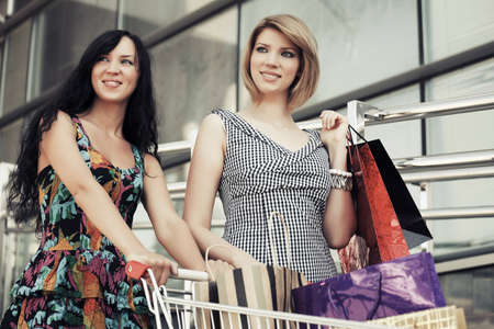 Two young fashion women with shopping cart in the mallの写真素材