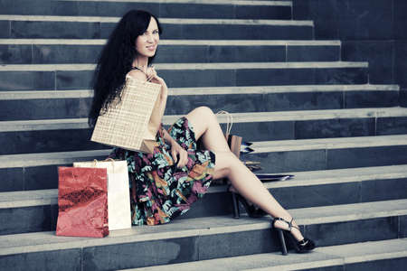 Happy young fashion woman with shopping bags on the mall stepsの写真素材