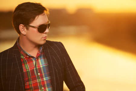 Portrait of young fashion man in sunglasses at sunsetの写真素材