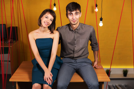 Happy young couple sitting on the desk in office