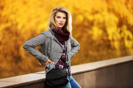 Young fashion blond woman in autumn city parkの写真素材