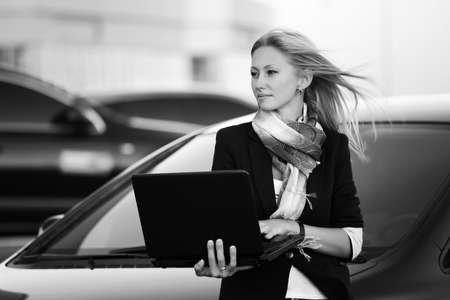 Young fashion business woman with laptop at the carの写真素材
