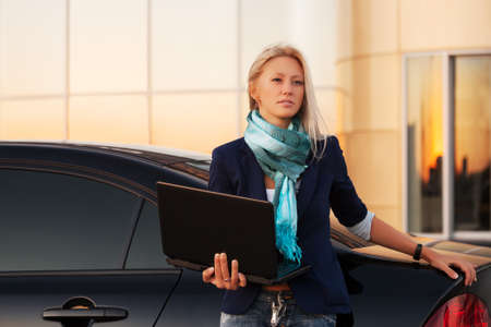 Young fashion business woman with laptop by her carの写真素材