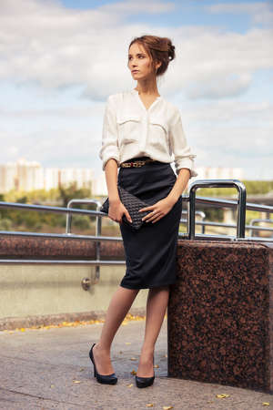 Young fashion business woman with handbag walking on the city streetの写真素材