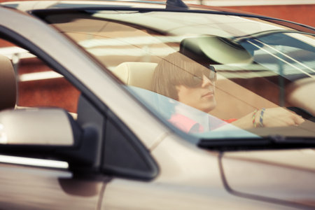 Young man in sunglasses driving convertible car